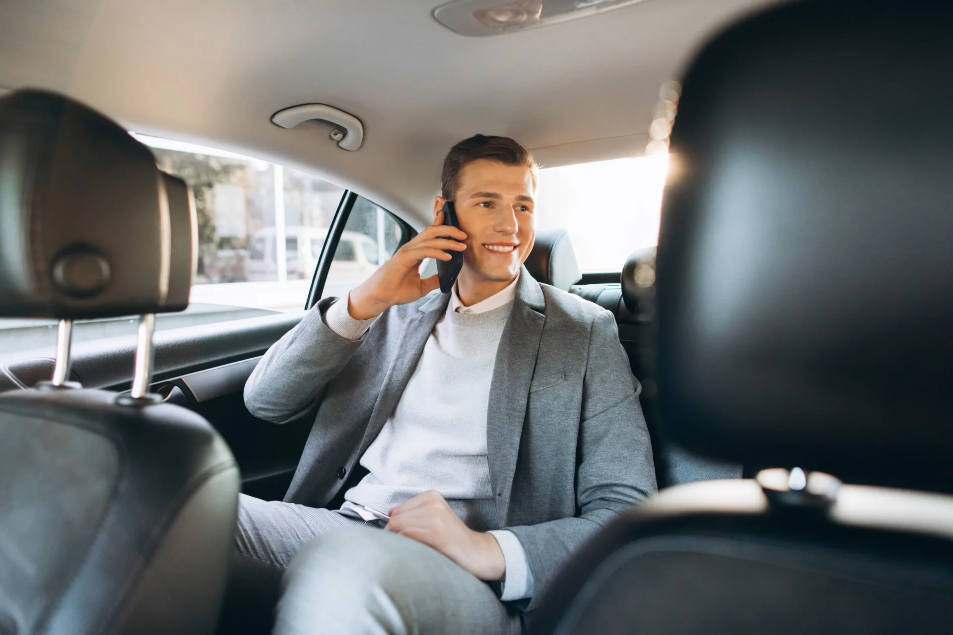 Young businessman talking mobile phone while sitting back seat car