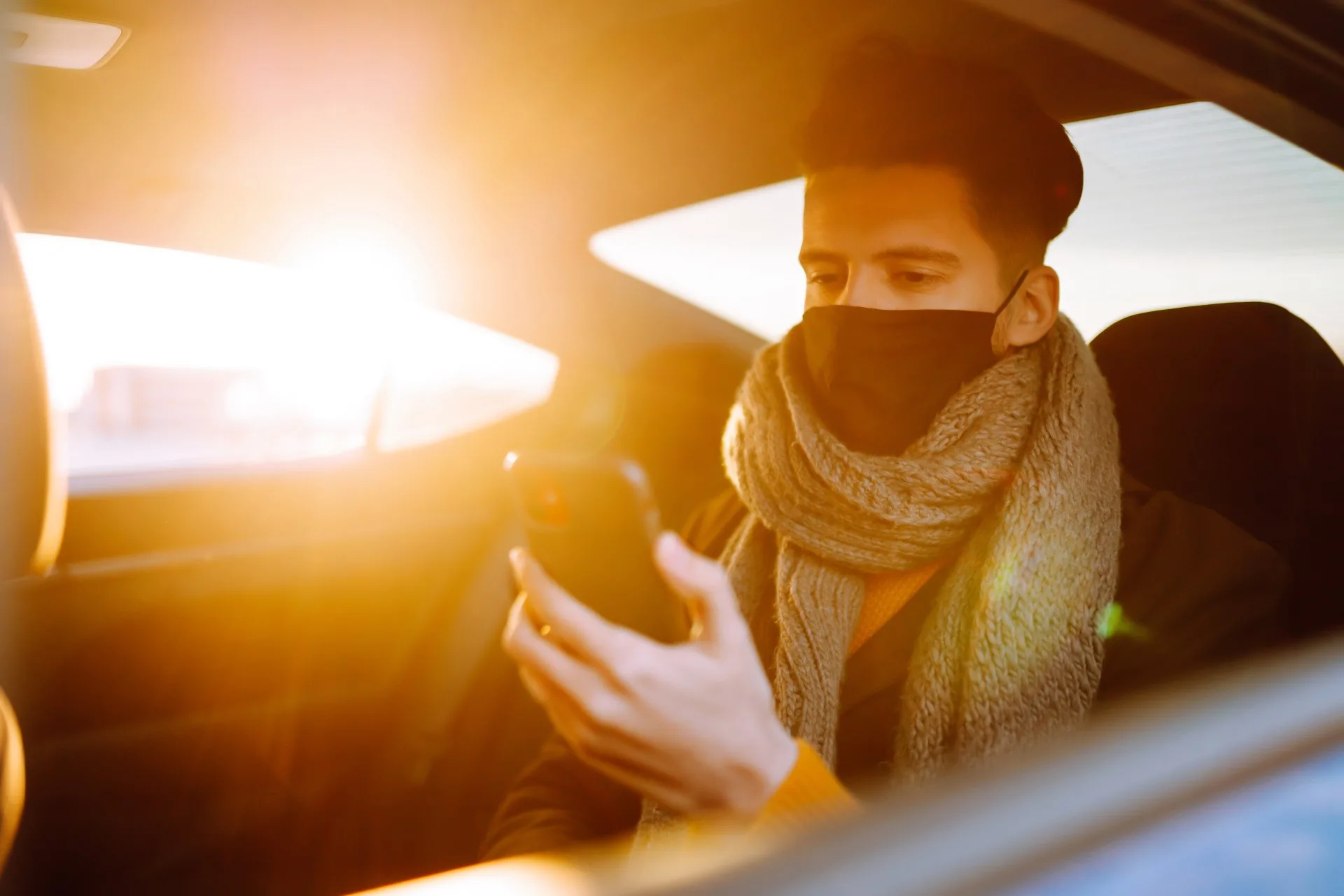 Young man protective sterile mask taxi car back seat checking her cell phone